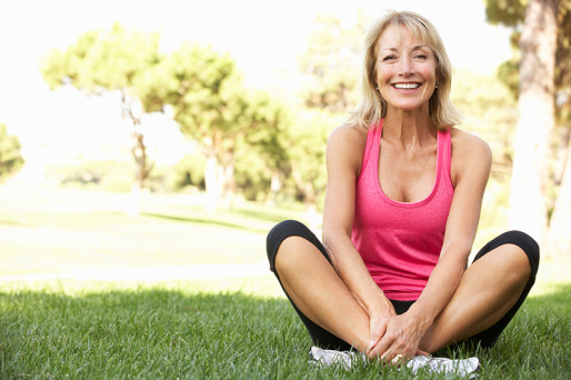 Woman in workout gear stretching on green grass
